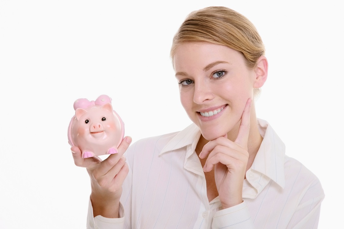 smiling woman with finger on cheek and questioning whilst holding piggy bank